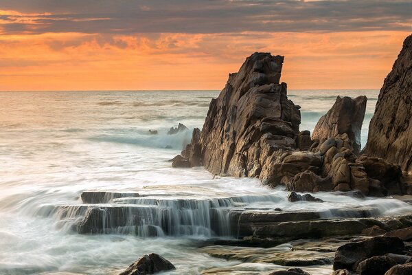 Rocas marinas en el fondo de una puesta de sol escarlata