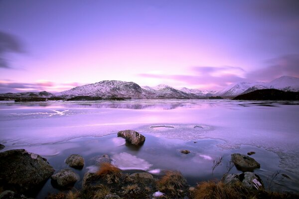 Snowy mountains and an icy lake at sunset