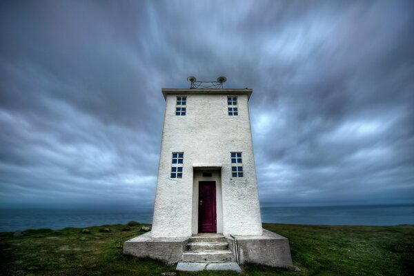 Phare en Islande, sur fond de ciel sombre avec des nuages et un paysage désertique