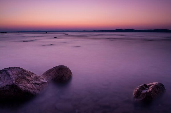 Lilac sunset over the sea with stones