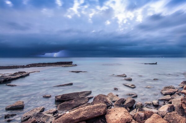 Rocks on the ocean shore under a blue sky