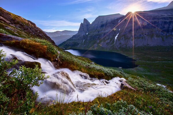 The sun appears over the mountains and lake