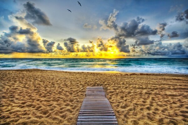 Playa de arena en el horizonte fuego al atardecer y nubes de plomo