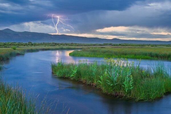 Lightning in the mountains on the background of the river