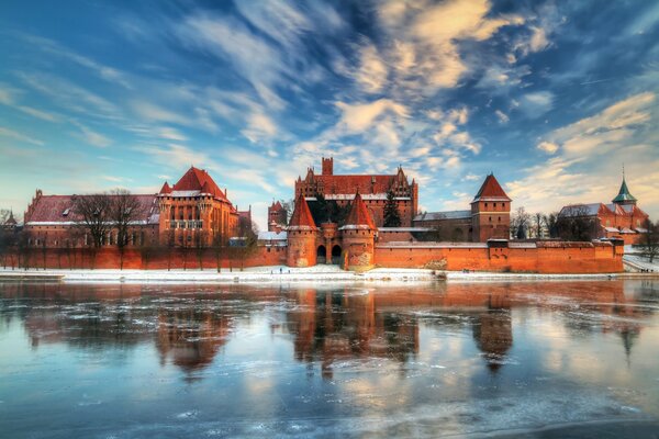 Castello in Polonia in inverno vicino a un lago ghiacciato in riflessione