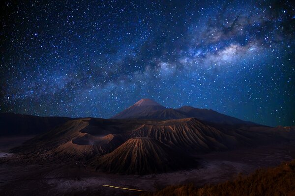 Индонезия, на острове вулкан, а над ним прекрасное звёздное небо