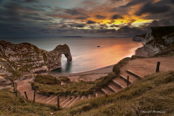 Stairs to the sea and the arch at sunset