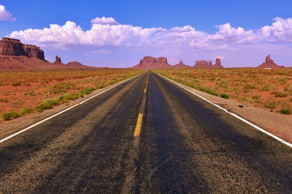 La route qui va au loin sur les côtés des paysages de plaines et de falaises