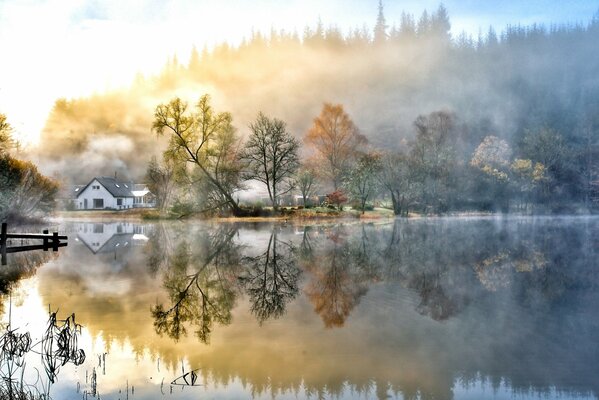 Árboles de otoño junto al lago y la casa blanca