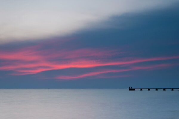 Muelle en el mar con puesta de sol vespertina