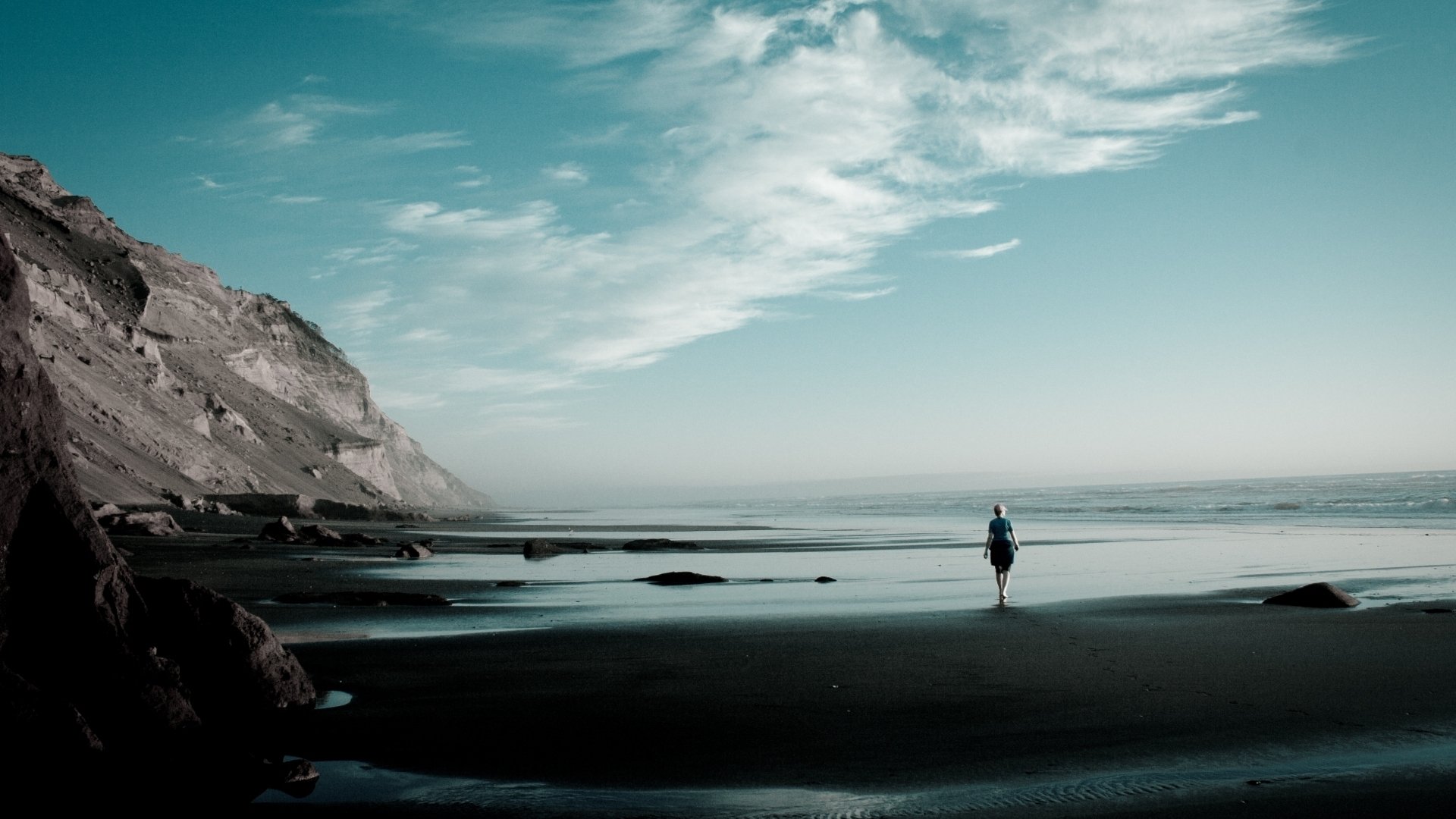 mer océan côte côte sable montagnes pente pierres fille horizon ciel nuages surf