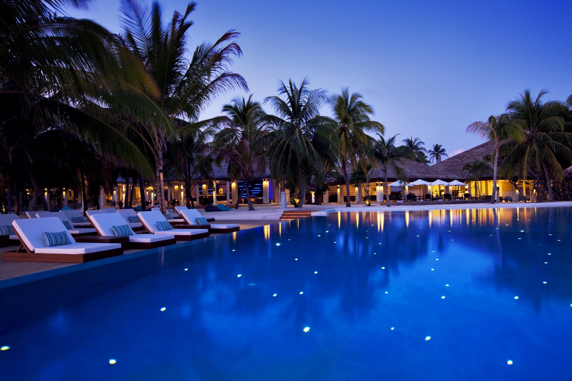 maldivas hotel velassaru noche piscina tumbonas árboles palmeras