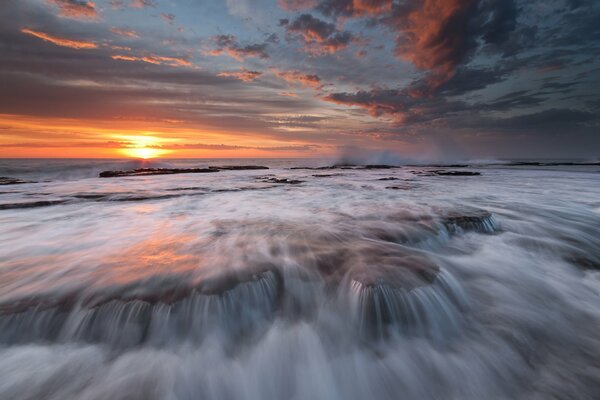 Flussi di acqua gorgogliante del mare al tramonto