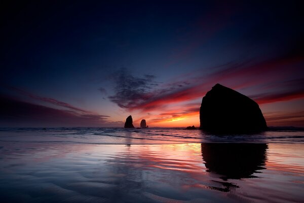 Mar al atardecer con siluetas de rocas