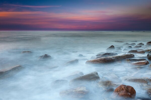 Mare calmo con pietre e bellissimo tramonto