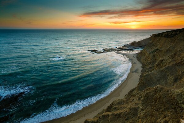 Les vagues battent le rivage dans les rayons du coucher du soleil