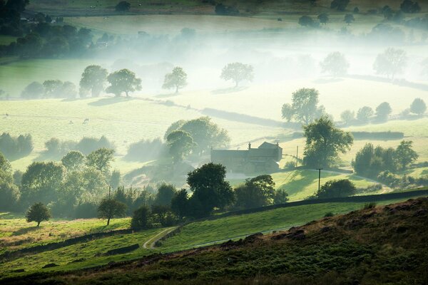 Granja del valle en la niebla por la mañana