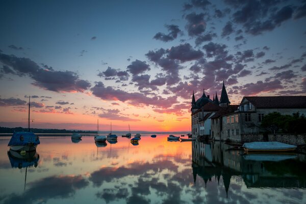 A house by the water and a boat in the sunset