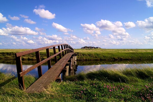 Un pont en bois sur la rivière relie deux champs