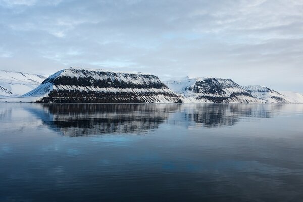 Schöne schneebedeckte Berge spiegeln sich im Wasser wider