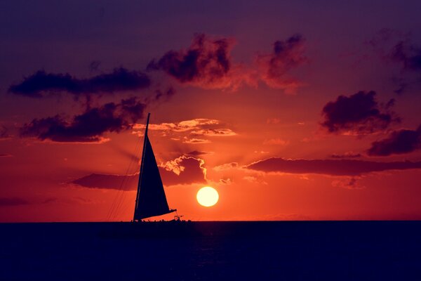 Voilier dans la mer sur fond de coucher de soleil