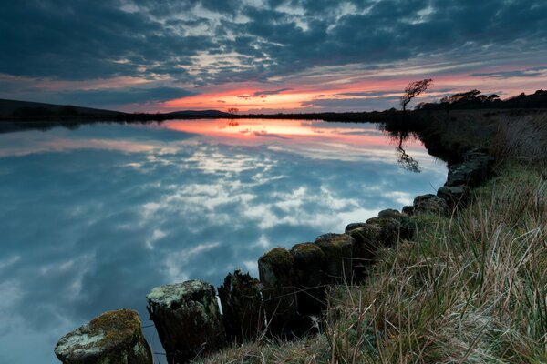 Roter Sonnenuntergang am nebligen See