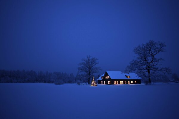 Ein Haus, das in der Nacht zu Weihnachten in einem schneebedeckten Tal steht