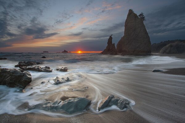 Puesta de sol en el mar el mar lava las piedras