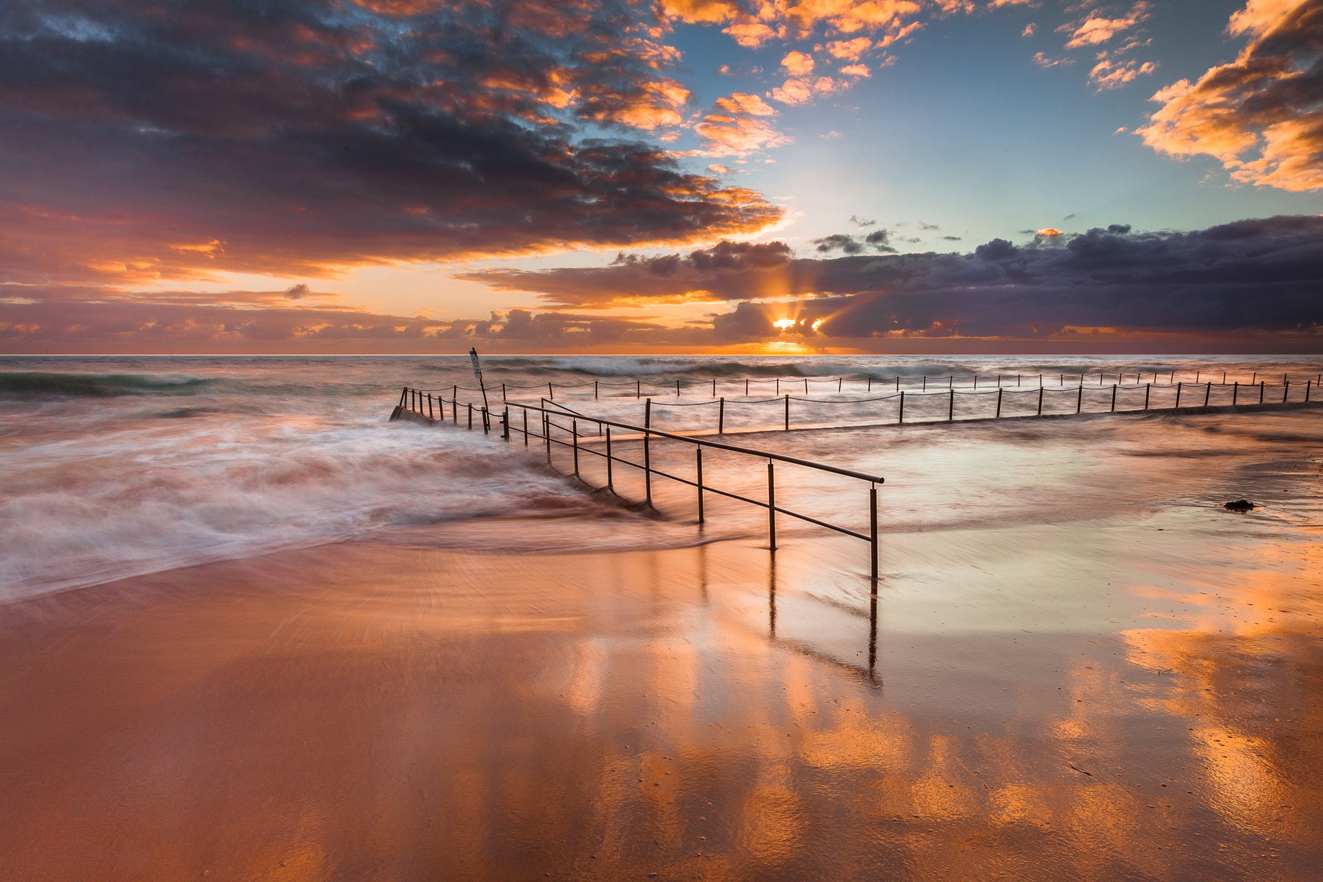 australia sea ocean beach fence chains sky sun clouds ray