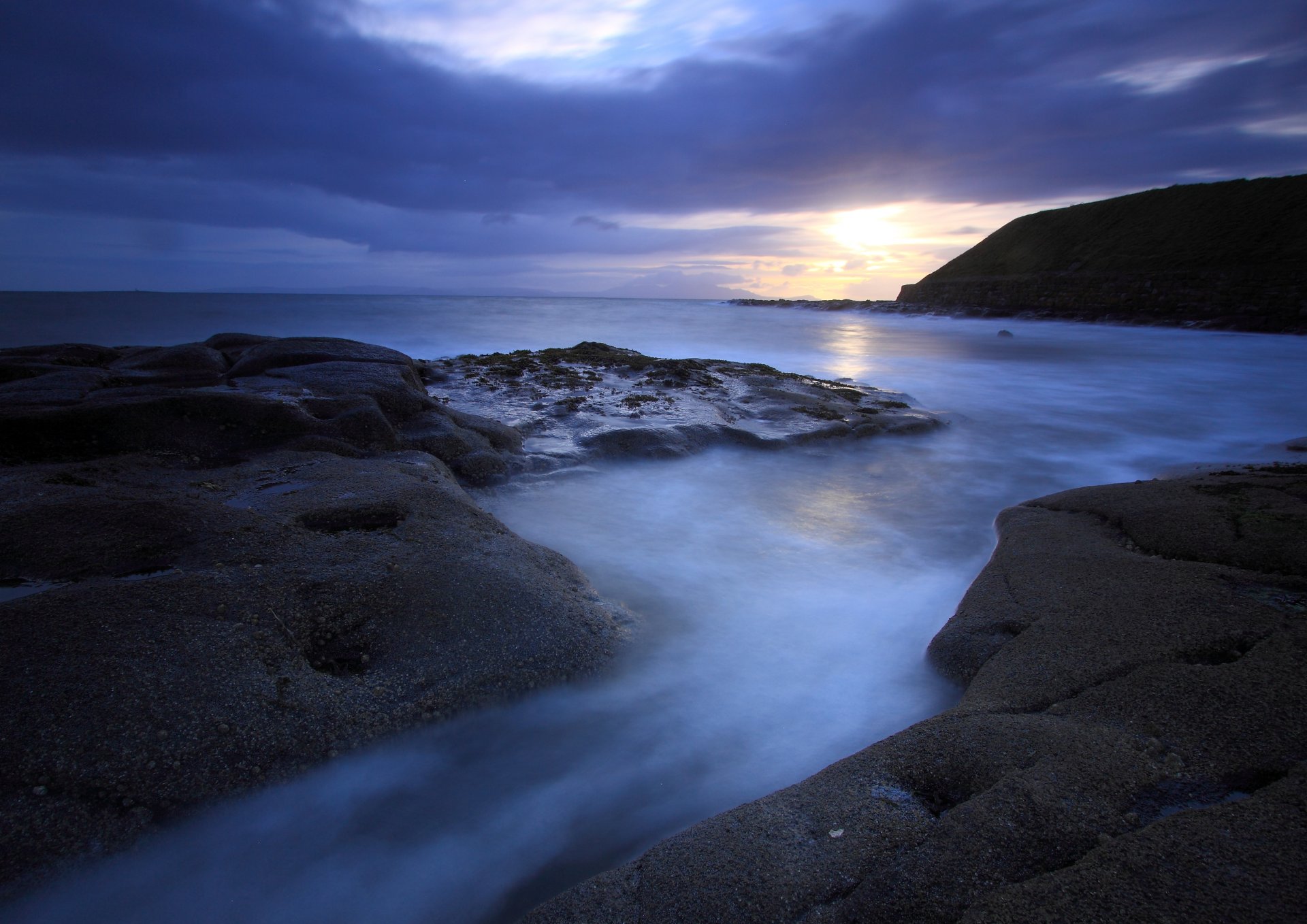 night sea ocean beach stones mountain away sun sunset sky clouds blue