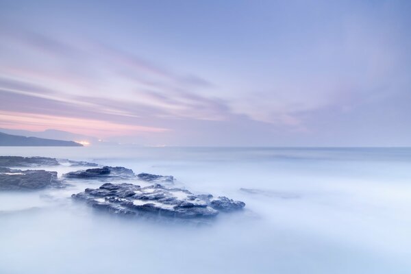 Brumoso amanecer sobre las rocas en el océano