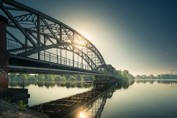 Eine Bogenbrücke über den Fluss zum anderen Ufer, wo die Sonne scheint