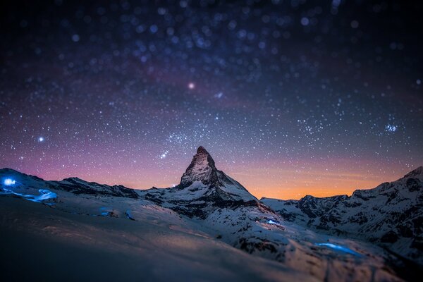 Sternenhimmel an den Spitzen der schneebedeckten Gipfel