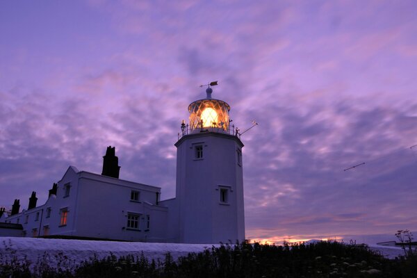 Lighthouse light in the twilight of the lilac sky