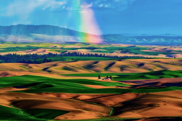 Rainbow on the background of the valley of fields