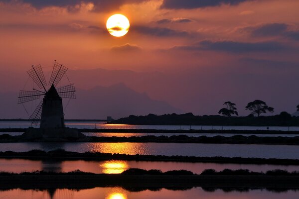 Reflection of the mill and the sun at sunset