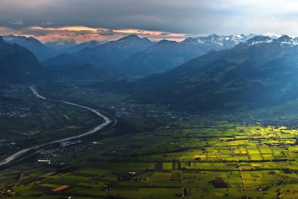 Valle delle montagne vicino al fiume al tramonto