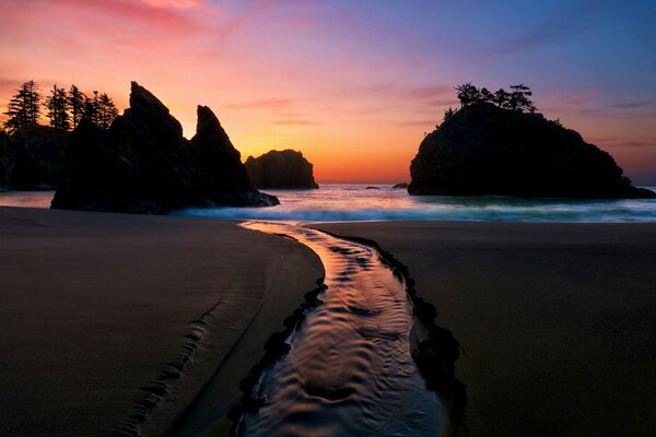 Romántico paisaje marino-bosque y rocas en el fondo de la puesta de sol reflejada en el agua