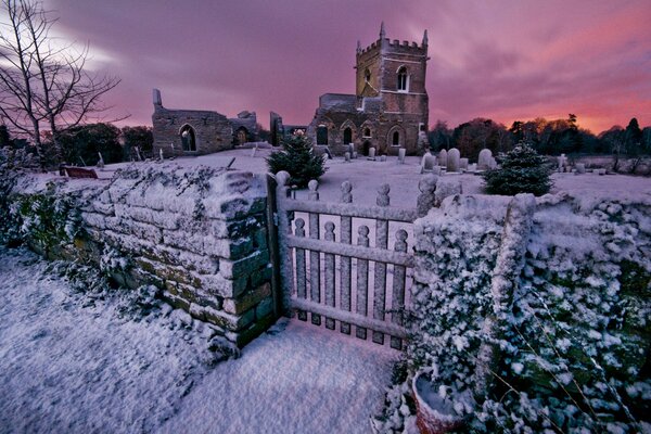 Kirche mit Friedhof im Winter bei Sonnenuntergang