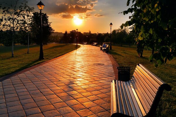 Park with benches under a sunset cloudy sky