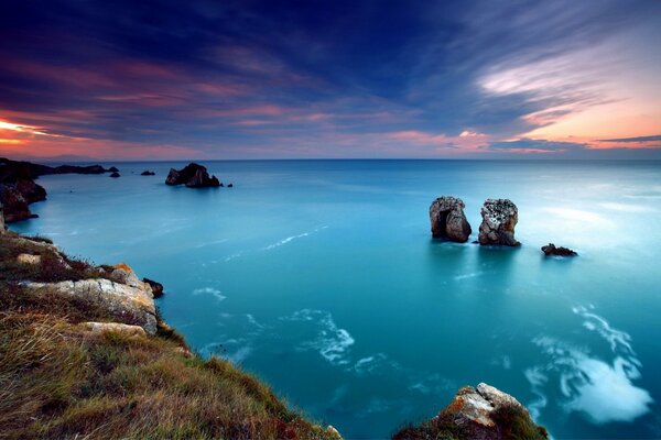 Cliffs in the azure sea at sunset