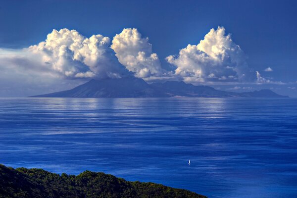 Sailboat in the sea against the background of mountains and clouds