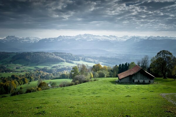 Haus auf einem grünen Hügel. Berge am Horizont