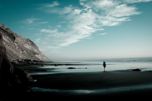 Lonely girl by the ocean and high rocks