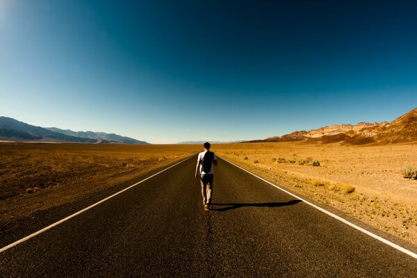 Un homme marche sur une route déserte