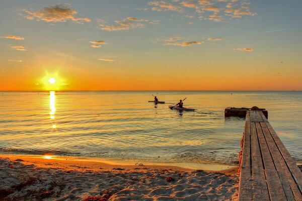 Menschen im Meer auf Booten bei Sonnenuntergang