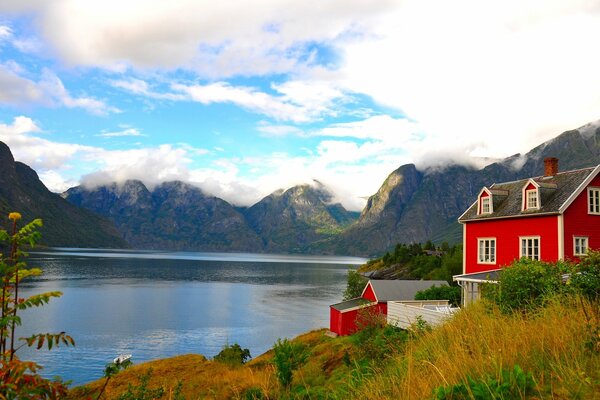 A house on the shore of a lake and majestic mountains