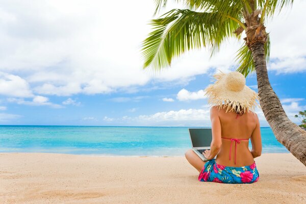 Mädchen schreibt einen Artikel in einem Laptop, der am Meer sitzt