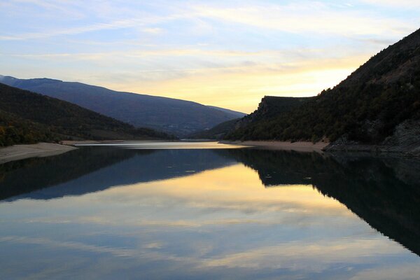 The sky and mountains are reflected in the lake