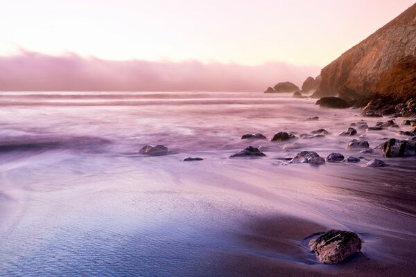 Waves of the sea on the beach surrounded by rocks